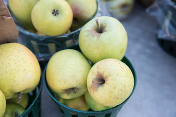 Fresh Mutsu Apples being sold at the market on a busy morning. The large amount of vegetables and fruits look fresh and several varieties of each are seen.