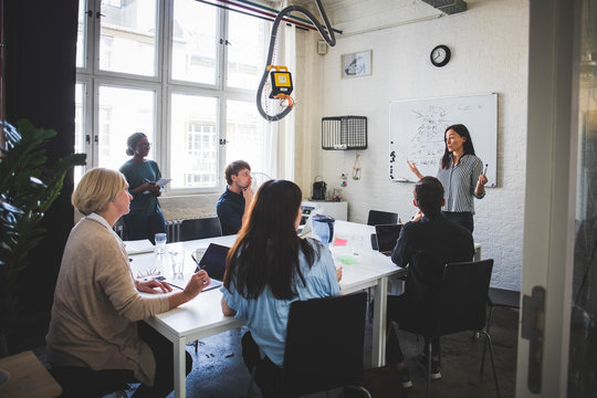 Businesswoman explaining colleagues during meeting in creative office