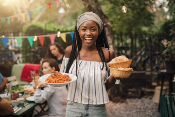 Portrait of smiling young woman with food standing in backyard