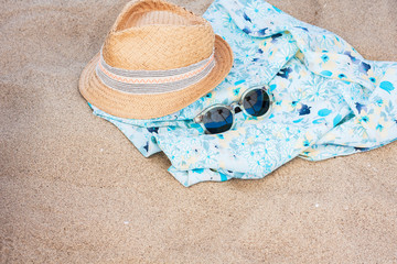 Vintage summer wicker straw hat with colorful ribbon, beach blue blanket, pareo and sunglasses on the beach 