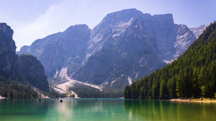 Panoramic view on emerald waters of Lago di Braies in Prags in Italian Dolomites (South Tyrol) with boats and tourists in a distance on a sunny summer day