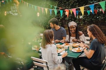 Friends having food at table during  party in backyard