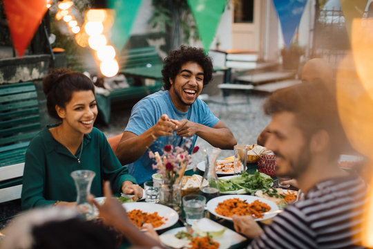 Smiling friends having food during party in backyard