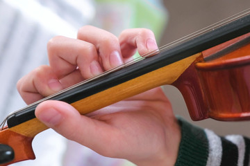 Violin in boy's hands. Boy is learning to play violin. Correct setting of the fingers of the left hand on the strings of the violin.