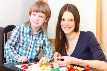 Cute boy and his mother play colorful play-dough together.