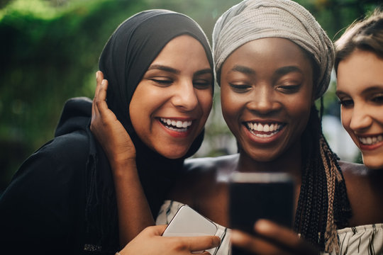 Smiling friends taking selfie through smartphone in backyard