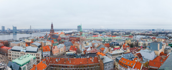 Naklejka na ściany i meble Aerial panoramic view of the Riga old town during winter day. Snowing in Riga. Top view of Dome Cathedral, statue of liberty, Daugava river and national library. Panorama