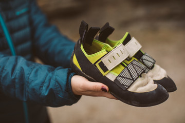 Climber woman with her climbing shoes placed on her hands.