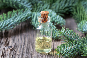 A bottle of fir essential oil with fresh fir branches