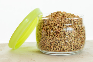 Opened can of green buckwheat on white background.