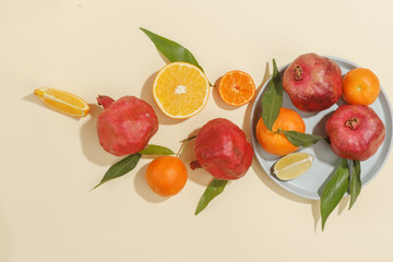 Fresh juicy tangerines, pomegranates and sliced fruits on a yellow background. Summer mood, healthy food. Top view.