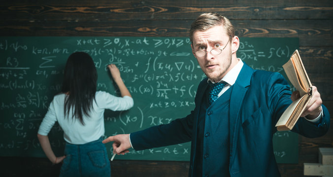 Education concept. Education of surprised teacher man point finger at woman student doing sums on chalkboard