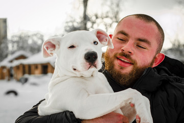 dog pit bull and her friend, her loving master who holds the dog in her arms, hugs and kisses. The...