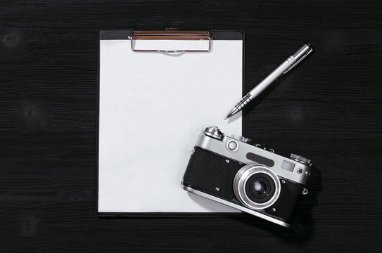 Shot list mockup. Photo session contract template. Vintage film photo camera and blank paper page on black wooden table background. Flat lay design.