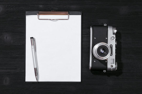 Shot list mockup. Photo session contract template. Vintage film photo camera and blank paper page on black wooden table background. Flat lay design.