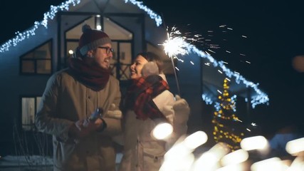 Young happy Couple With Sparklers Celebrating christmas outdoors. Family with festive bright. Merry christmas and Happy new year