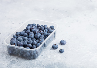 Plastic tray container of fresh organic healthy blueberries on stone kitchen table background. Space for text