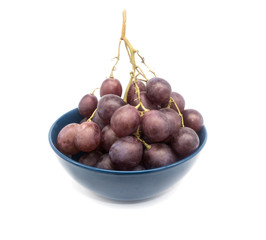 Bunch of purple grapes in a plate isolated on white background