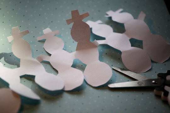 Leporello aus gebastelten und ausgeschnittenen Schneem&auml;nner aus Papier, die sich an den H&auml;nden halten