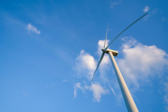 View up, bottom view of wind turbine, windmill isolated on blue sky background. Royalty high-quality free stock photo image looking up wind turbine, windmill energy converter in a blue sky background