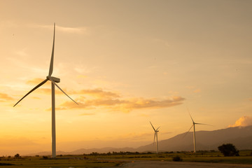 Wind turbine farm or windmill on golden sunset sky in summer day. High-quality stock photo image of wind turbine or windmill for clean energy concept. Energy Production with clean and Renewable Energy