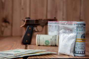 Stack of Money, drugsand a gun on a wooden table, concept about danger and threat of the drug