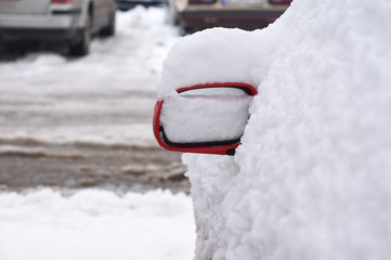 Car mirror in snow. Snow covered side view mirror of a modern car