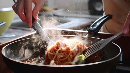 Cooking and stirring the spaghetti with red tomato sauce in the frying pan. - Powered by Adobe