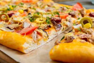 Tasty pizza with mushrooms, chicken, pepperoni, olives, corn cut into pieces. Close up