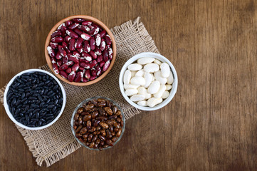 Assortment of colorful raw beans in bowls on a wooden table. Healthy food, dieting, nutrition concept. Legumes - vegan protein source.