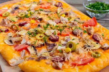 Tasty pizza with mushrooms, chicken, pepperoni, olives, corn cut into pieces. Close up