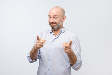 Portrait of happy mature man with beard pointing at you like saying Thank you for your help and...