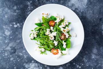 Homemade salad With rocket, Cheese Popcorn and tomatoes cherry on white plate on grey background menu photo