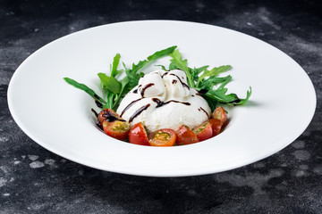 Italian cheese burrata with tomatoes and herbs on a dark background