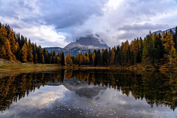 Autumn landscape of Antorno lake with famous Dolomites mountain peak of Tre Cime di Lavaredo in background in Dolomites, Italy. Beautiful nature scenery and scenic travel destination in Fall time.