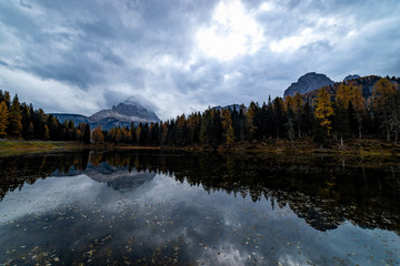 Obraz premium Autumn landscape of Antorno lake with famous Dolomites mountain peak of Tre Cime di Lavaredo in background in Dolomites, Italy. Beautiful nature scenery and scenic travel destination in Fall time.