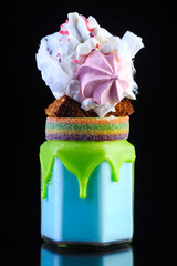 Milk bright coctail with whipped cream in glass decorated with sweets and cholocale black background with reflection