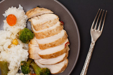 Baked chicken breasts or fillet on plate with rice and vegetables on plate.