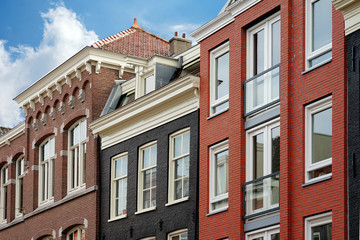 A number of houses in the traditional Dutch architectural style. Triangular roofs with orange tiles. A number of colorful old houses in Europe.