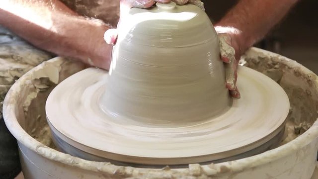     Artist potter in the workshop creating a ceramic vase. Hands closeup. Twisted potter's wheel. Small artistic craftsmen business concept. 