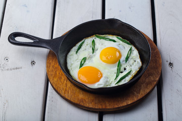 Fried eggs for delicious healthy easy breakfast on a table. Fresh homemade meal on a frying pan. Traditional breakfast food.