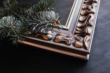 Corner of vintage photo frame and pine branch on black background.