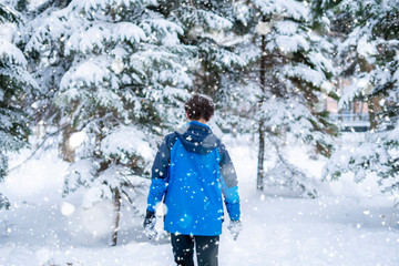 Fototapeta na wymiar young portrait of male teenager walking in the winter snowy forest f