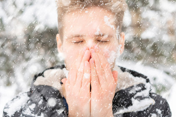 close up man portrait warm up and heating hands near mouth outdoors on a winter day f