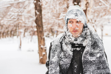 close up portrait of frost man face covered by snowy scarf and hat outdoor, winter concept f