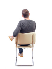 Back view of a man sitting on a chair.