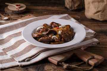 Pickled mushrooms in white bowl on wooden background countryhouse style salt pepper