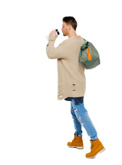 back view of walking  man  with coffee cup and green bag.