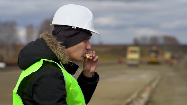 Engineer sitting on the road, eating a sandwich. Lunch break.