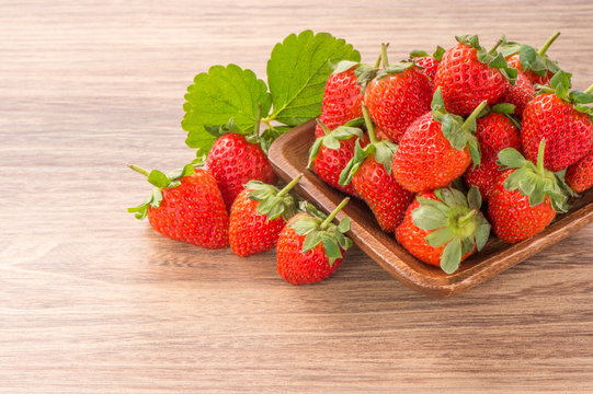 A plate of beautiful strawberries isolated on wooden background, close up, macro.